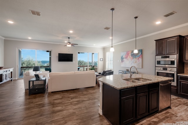 kitchen featuring ceiling fan, dark brown cabinetry, sink, decorative light fixtures, and light stone countertops