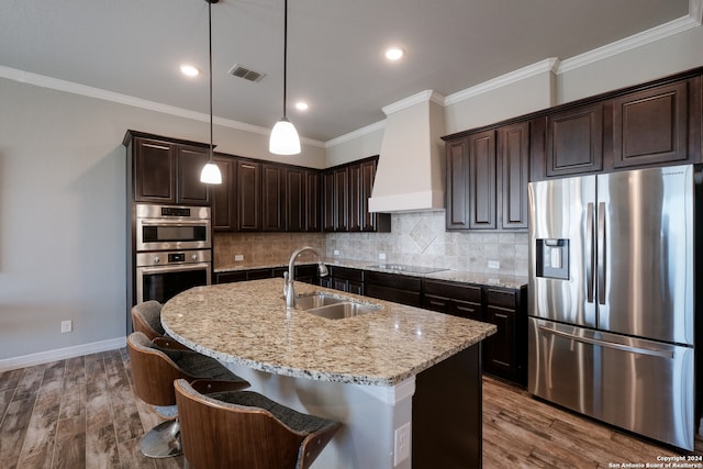 kitchen featuring a center island with sink, appliances with stainless steel finishes, hardwood / wood-style floors, and sink