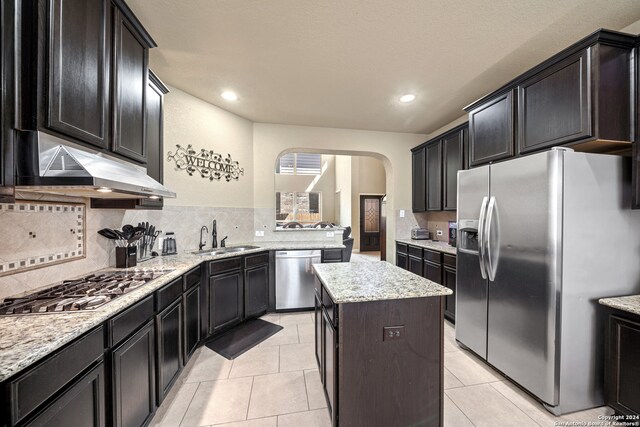 kitchen featuring light tile patterned flooring, sink, a kitchen island, decorative backsplash, and appliances with stainless steel finishes