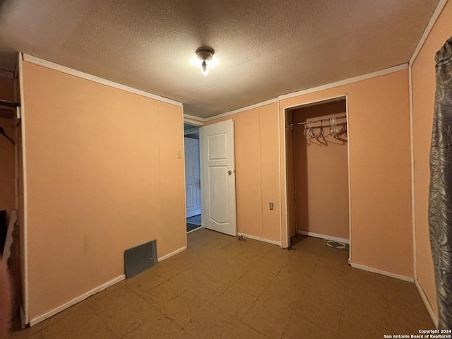 unfurnished bedroom featuring a textured ceiling, a closet, baseboards, ornamental molding, and tile patterned floors