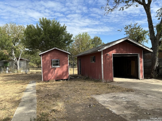 view of outbuilding featuring an outbuilding, driveway, and fence