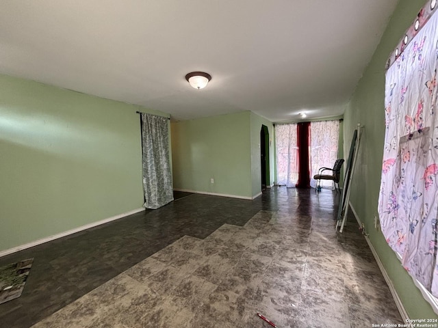 spare room with arched walkways, tile patterned floors, and baseboards