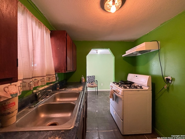 kitchen featuring a textured ceiling, white gas stove, sink, and exhaust hood