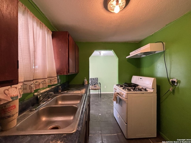 kitchen featuring arched walkways, under cabinet range hood, a sink, white range with gas stovetop, and a textured ceiling
