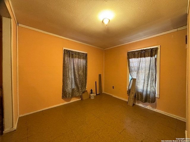 empty room featuring a textured ceiling and ornamental molding