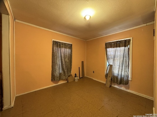 unfurnished room with baseboards, ornamental molding, and a textured ceiling