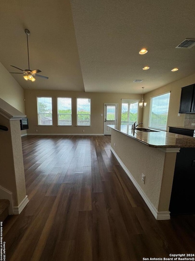 unfurnished living room featuring sink, ceiling fan with notable chandelier, and dark wood-type flooring