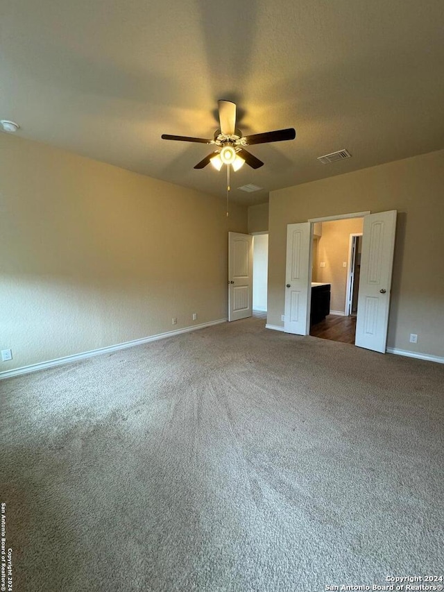 unfurnished bedroom with ceiling fan and dark carpet