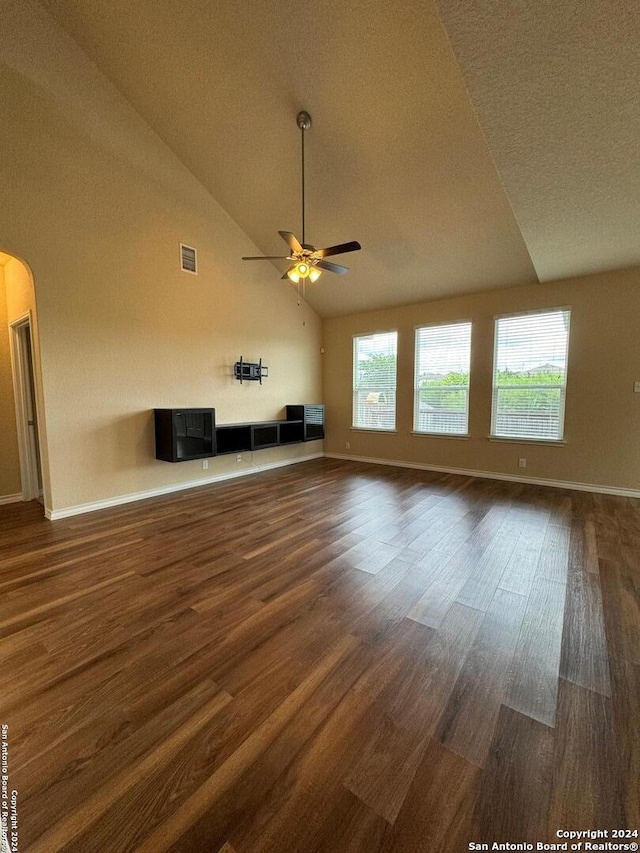 unfurnished living room with lofted ceiling, ceiling fan, dark wood-type flooring, and a textured ceiling