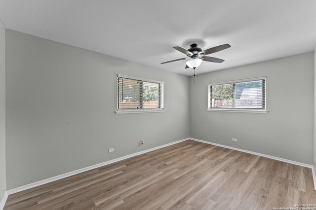 empty room with a healthy amount of sunlight, light hardwood / wood-style floors, and ceiling fan