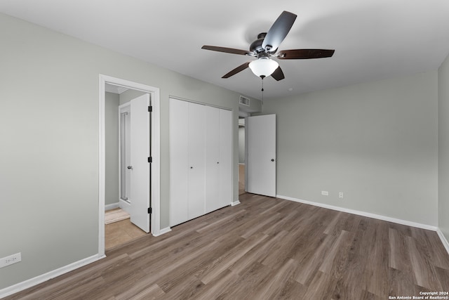 unfurnished bedroom featuring ensuite bath, ceiling fan, a closet, and hardwood / wood-style flooring