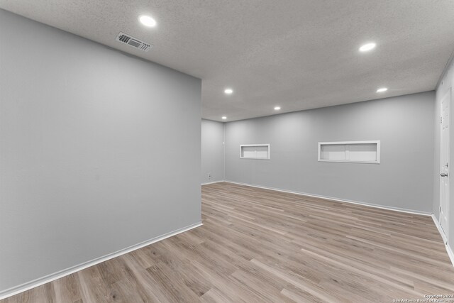 spare room with light wood-type flooring and a textured ceiling