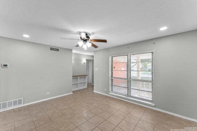 tiled spare room featuring ceiling fan