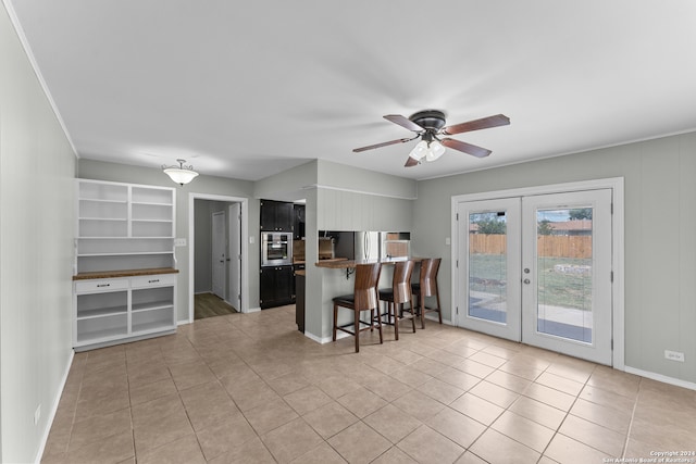 kitchen featuring ceiling fan, light tile patterned flooring, kitchen peninsula, appliances with stainless steel finishes, and a breakfast bar area