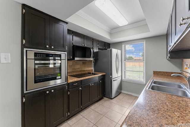 kitchen with appliances with stainless steel finishes, tasteful backsplash, light tile patterned floors, a tray ceiling, and sink