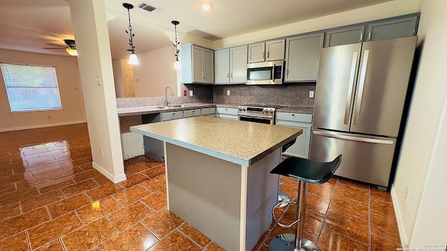 kitchen with pendant lighting, sink, tasteful backsplash, appliances with stainless steel finishes, and a kitchen bar