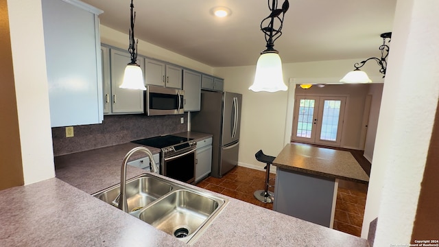 kitchen featuring appliances with stainless steel finishes, kitchen peninsula, gray cabinets, decorative light fixtures, and sink