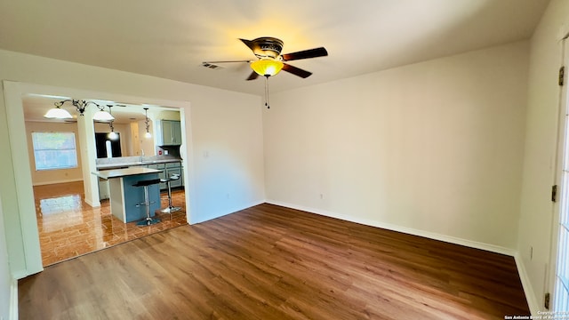 unfurnished living room with sink, ceiling fan, and hardwood / wood-style flooring