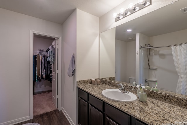 bathroom with walk in shower, wood-type flooring, vanity, and toilet