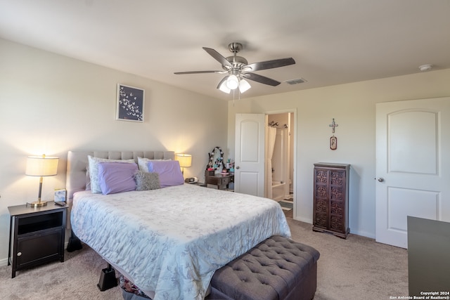 bedroom with light colored carpet, ceiling fan, and ensuite bathroom