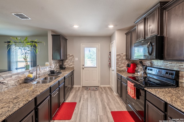 kitchen with light wood-type flooring, plenty of natural light, sink, and black appliances