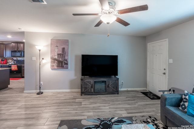 living room with ceiling fan and light hardwood / wood-style flooring