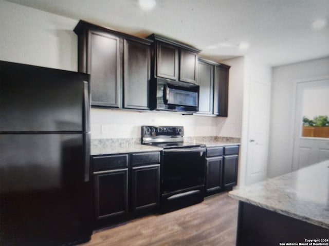 kitchen with dark brown cabinets, light wood-type flooring, and black appliances