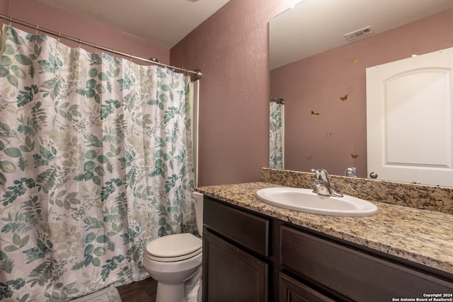 bathroom with curtained shower, vanity, and toilet