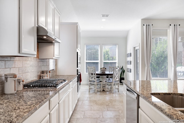 kitchen with white cabinetry, tasteful backsplash, light stone countertops, stainless steel appliances, and lofted ceiling