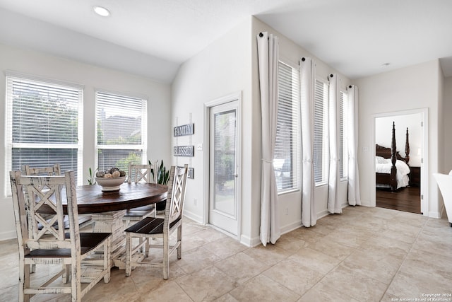 dining space with lofted ceiling, light tile patterned floors, and a healthy amount of sunlight