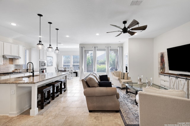 tiled living room with ceiling fan and sink