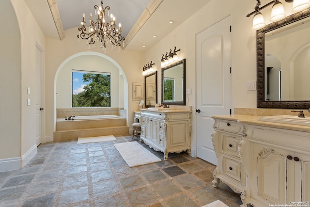 bathroom featuring lofted ceiling, a chandelier, tiled tub, and vanity