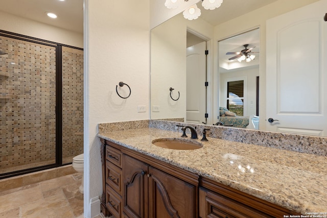 bathroom featuring ceiling fan, a shower with door, vanity, and toilet