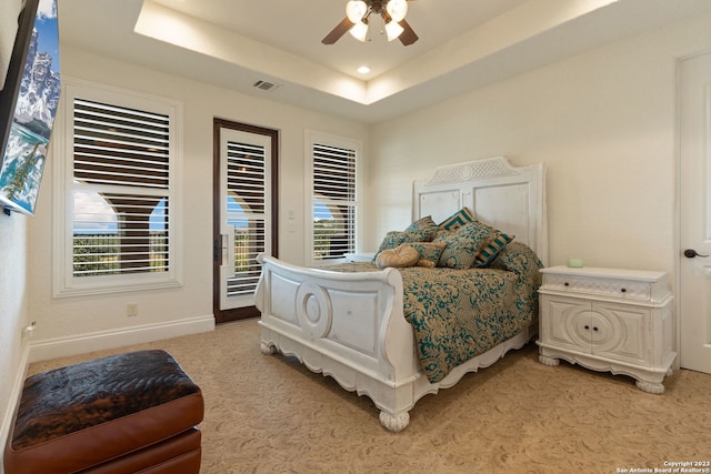 bedroom featuring light carpet, ceiling fan, a raised ceiling, and access to outside