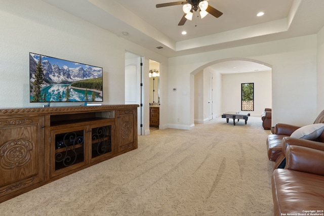 carpeted living room featuring a raised ceiling and ceiling fan