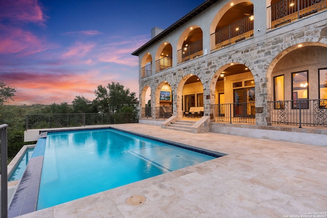 pool at dusk featuring a patio area