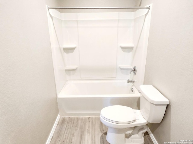 bathroom with wood-type flooring, tub / shower combination, and toilet