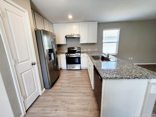 kitchen featuring white cabinets, sink, stone countertops, stainless steel appliances, and light wood-type flooring