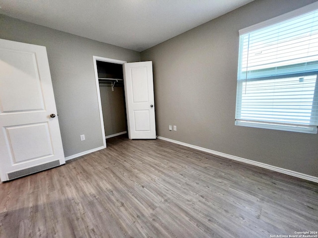 unfurnished bedroom with light hardwood / wood-style flooring, a closet, and multiple windows