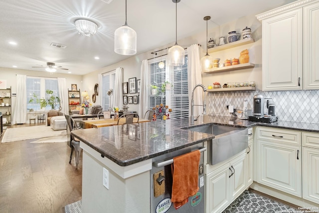 kitchen with dishwasher, dark wood-type flooring, dark stone counters, sink, and decorative light fixtures