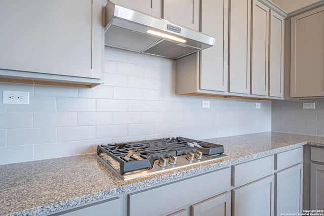 10280 Bartenheim Dr, Schertz, TX 78154 - kitchen with under cabinet range hood, stainless steel gas stovetop, decorative backsplash, and gray cabinets