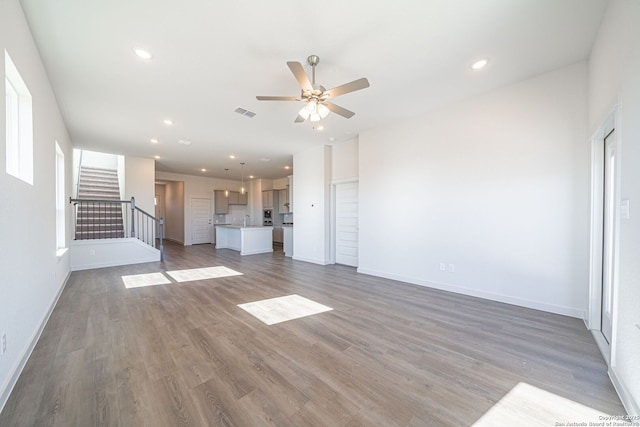 10280 Bartenheim Dr, Schertz, TX 78154 - unfurnished living room featuring stairway, a ceiling fan, wood finished floors, baseboards, and recessed lighting