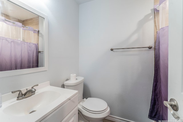 bathroom featuring curtained shower, vanity, and toilet