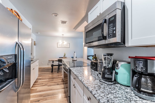 kitchen with hanging light fixtures, light hardwood / wood-style flooring, white cabinetry, appliances with stainless steel finishes, and an inviting chandelier