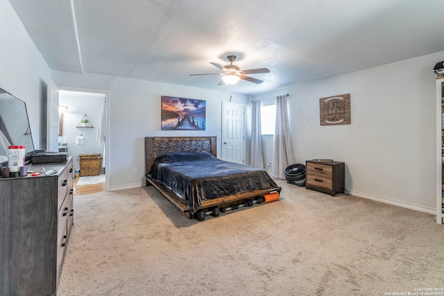 bedroom with light carpet, ceiling fan, a fireplace, and a textured ceiling