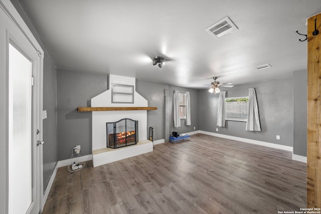 unfurnished living room with wood-type flooring, a multi sided fireplace, and ceiling fan