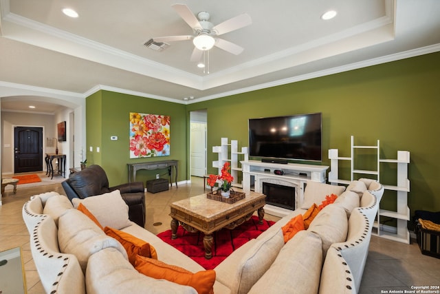 tiled living room with ceiling fan, a raised ceiling, and crown molding