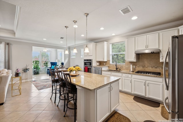 kitchen featuring appliances with stainless steel finishes, hanging light fixtures, a center island, and white cabinets