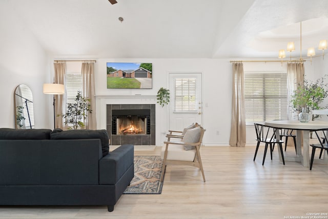 living room featuring light hardwood / wood-style floors, a tiled fireplace, and a chandelier