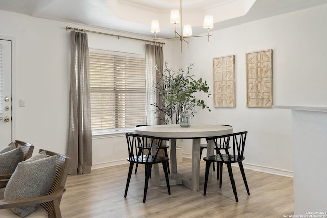 dining room with a tray ceiling, crown molding, a chandelier, and light hardwood / wood-style flooring